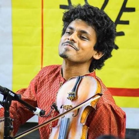 Sumanth Manjunath performs on violin while wearing a red patterned kurta.