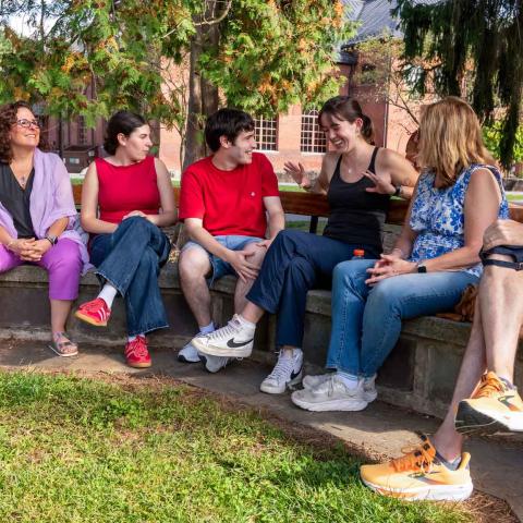 A group of people seated in a semi-circle on an outdoor area.