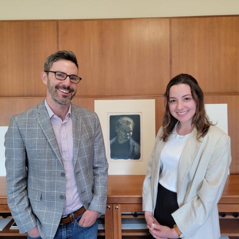 John Murphy and Ruby Funfrock stand in the Loeb's Print study room, with prints on the shelf behind them.