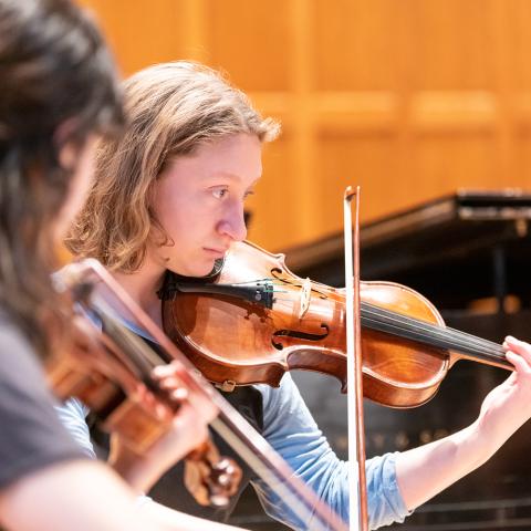 Two student violinists perform in a chamber music recital.