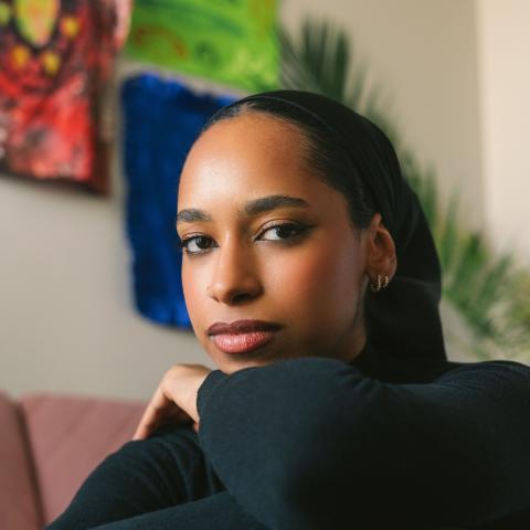 Portrait photo of artist Sarah Elawad, a person with long dark hair and dark clothing.