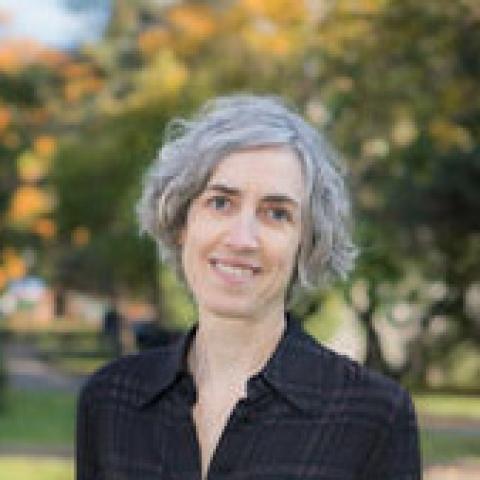 Smiling person with short gray hair, photographed outdoors.