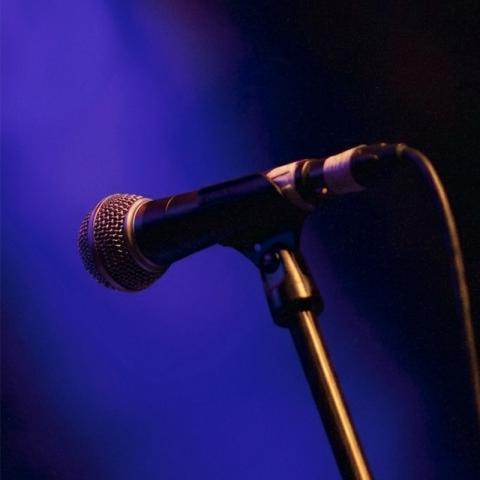 Decorative image of a microphone dramatically lit by a spotlight.
