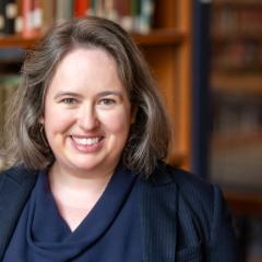 Portrait of a person with library book shelves in the background.