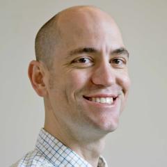 Photo portrait of a person in front of a grey wall.