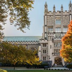 Gothic-style stone building on the Vassar campus framed by autumn trees with sunlight streaming through the leaves.