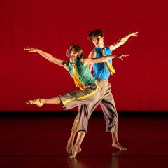 Two dancers perform on a dramatically lit stage.