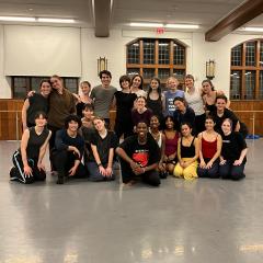 A group of dancers posing together in a studio, smiling and gathered in rows after a rehearsal.