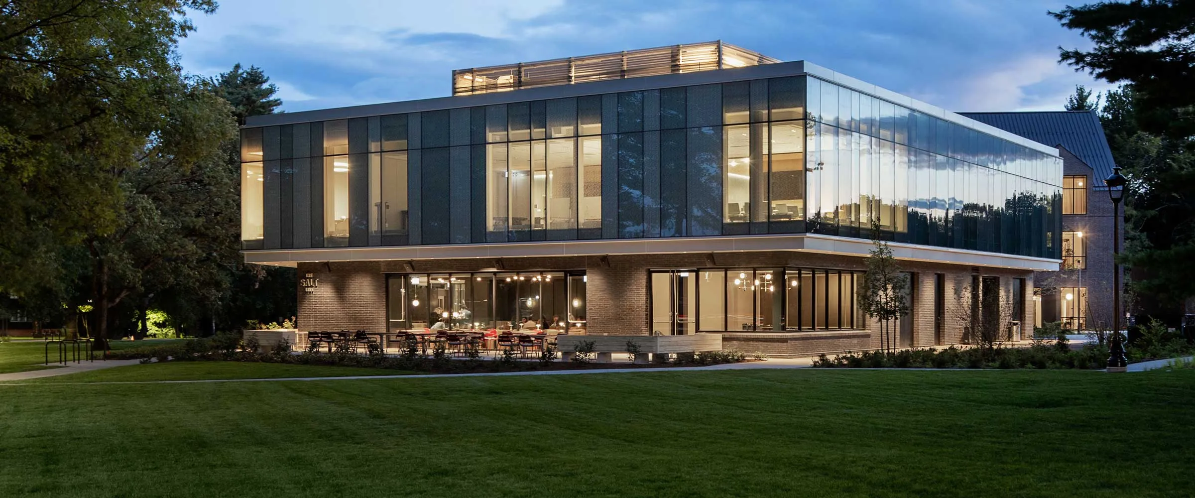 Glass and concrete buildings nestled within trees with foliage reflecting on the windows.