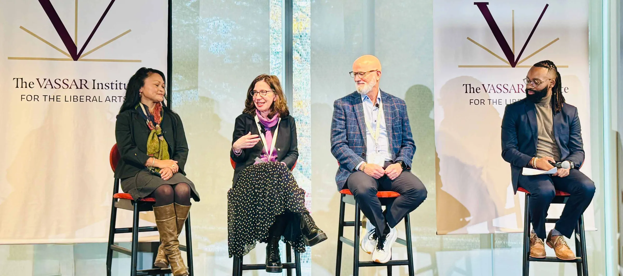 Four people sit on a brightly lit stage.